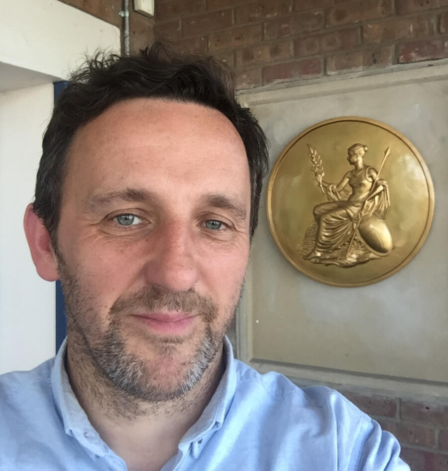 Roger Percy beside a gold Britannia medallion